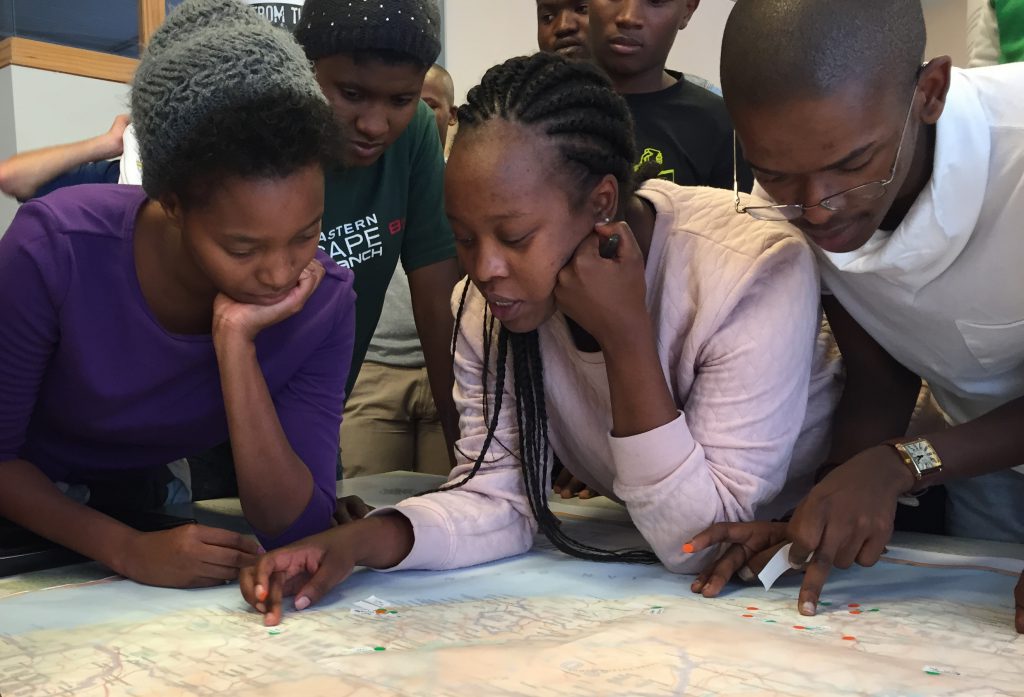 Equal Education leaders left to right: Whitney Cele, Nombulelo Nyathela (centre) and Bayanda Mazwi tracing their personal histories on a large map of South Africa