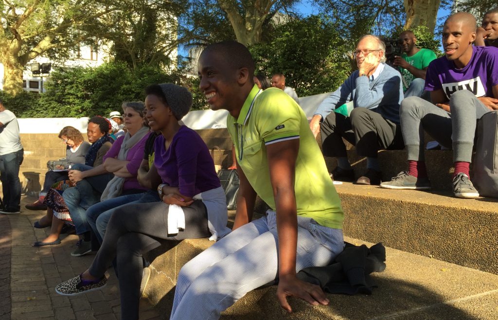 Students watch drama performed by their peers in front of the Natural History Museum in Cape Town with Professor Francis Wilson (top right)